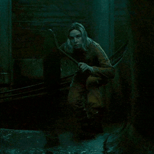 a woman in a dark room holding a sword