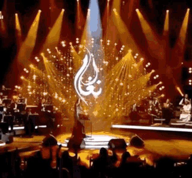a woman is dancing on a stage in front of a crowd of people in a dark room .