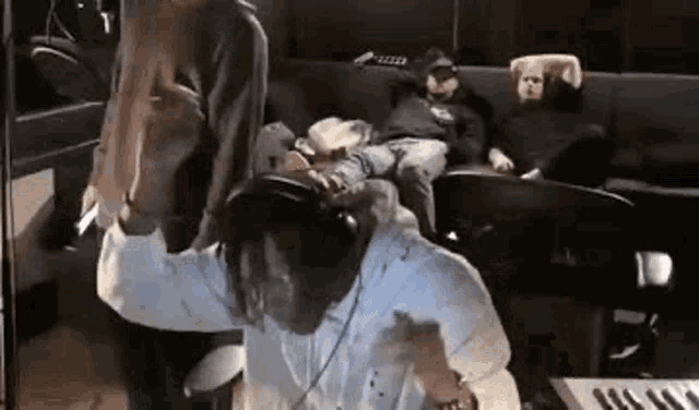 a group of people are sitting on a couch in a room . one of the people is wearing headphones and dancing .