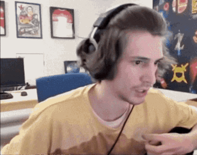 a man wearing headphones and a yellow shirt is sitting in front of a computer