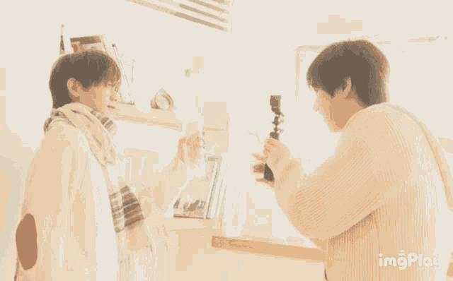 two men are standing next to each other in a room .