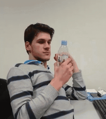 a man in a striped shirt holds a bottle of water