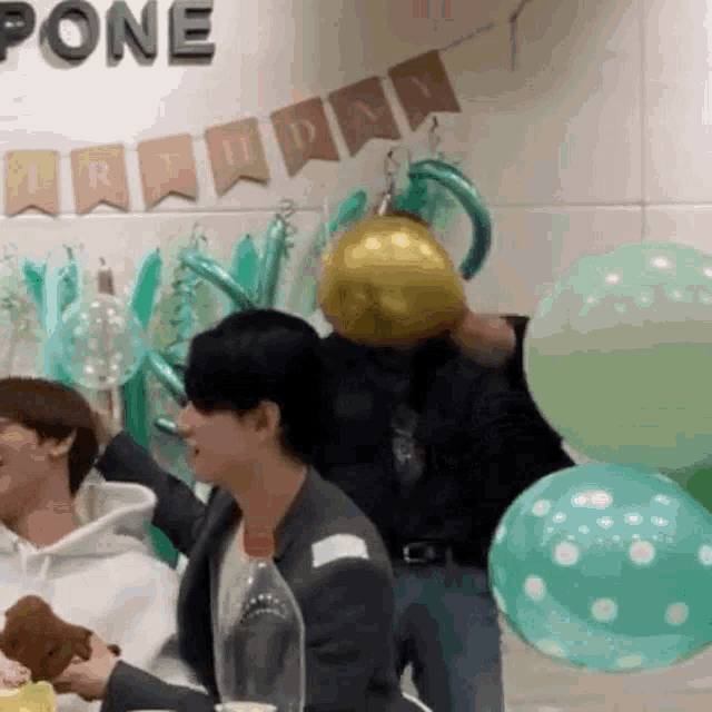 a group of people are sitting at a table with balloons and a banner that says pone