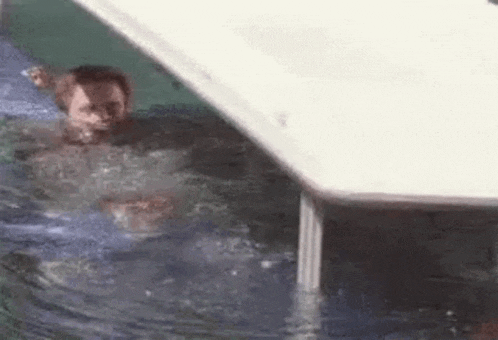 a man is swimming in a pool with a table in the water .
