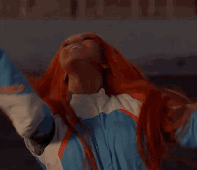 a woman with red hair is wearing a blue and white outfit and laughing .
