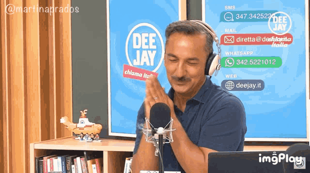 a man wearing headphones stands in front of a microphone with a deejay logo behind him