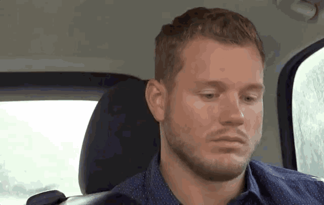 a man with a beard is sitting in the back seat of a car and looking at the camera .