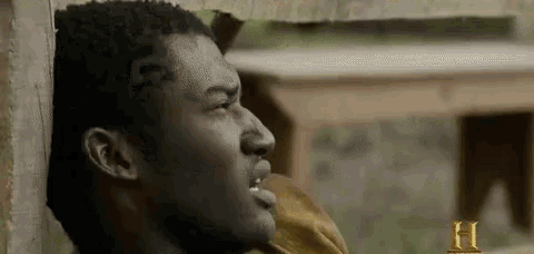 a man is leaning against a wall with his mouth open and looking at something .