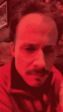 a close up of a man 's face with a red background .