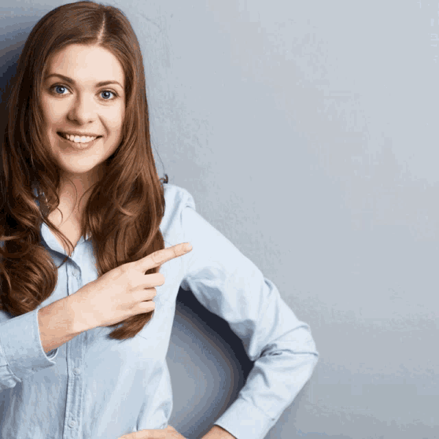 a woman in a blue shirt is pointing at herself