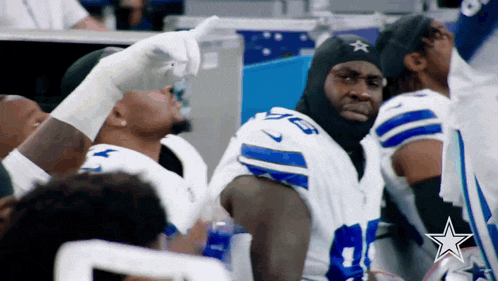 a group of cowboys players are sitting on the sidelines