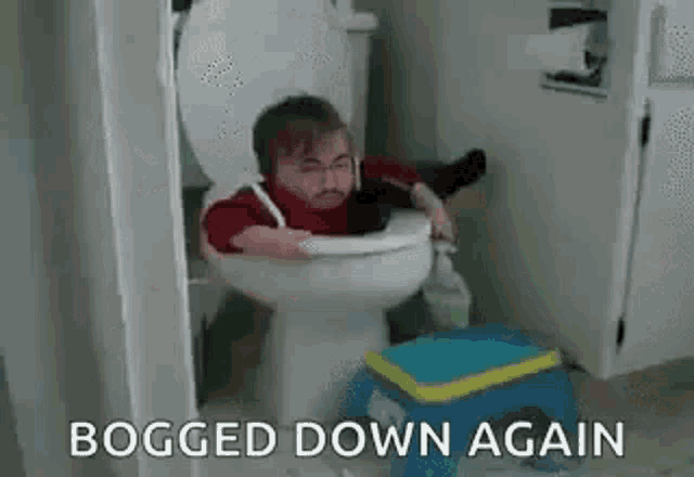 a man is sitting on a toilet with his legs crossed and a stool next to him .