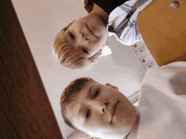 two young boys are looking up at the camera and one has a nose ring on