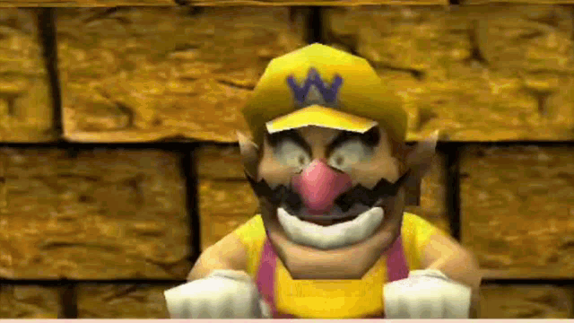 a cartoon character wearing a yellow hat with a blue letter w on it is standing in front of a brick wall .