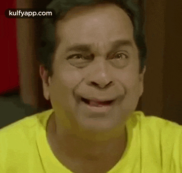 a man in a yellow shirt is making a funny face and smiling .