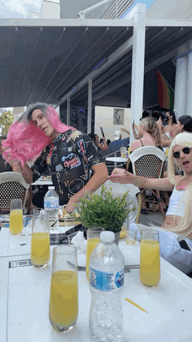 a bottle of aquafina water sits on a table in front of a man with pink hair