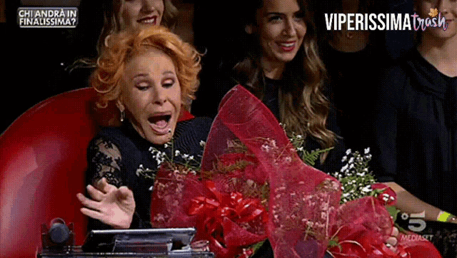 a woman is holding a bouquet of flowers in front of a screen that says viperissima on it