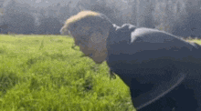 a man in a black jacket is standing in a field of grass .