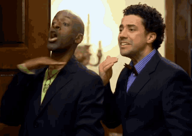 two men in suits and bow ties are standing next to each other and one has his mouth open