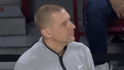 a man wearing a nike sweatshirt looks to his left