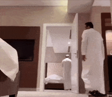 a man in a white robe stands in a room