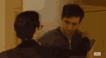 a man is looking at himself in a mirror while a woman looks on .