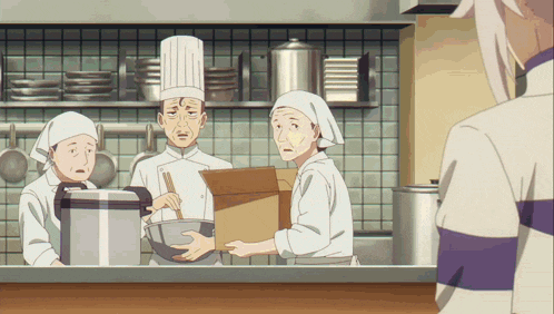 a man in a chef 's hat is standing in a kitchen holding a box