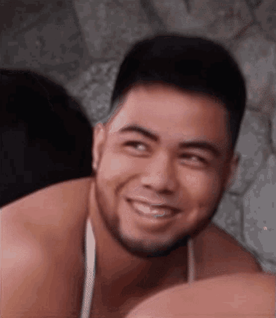 a shirtless man with a beard is smiling