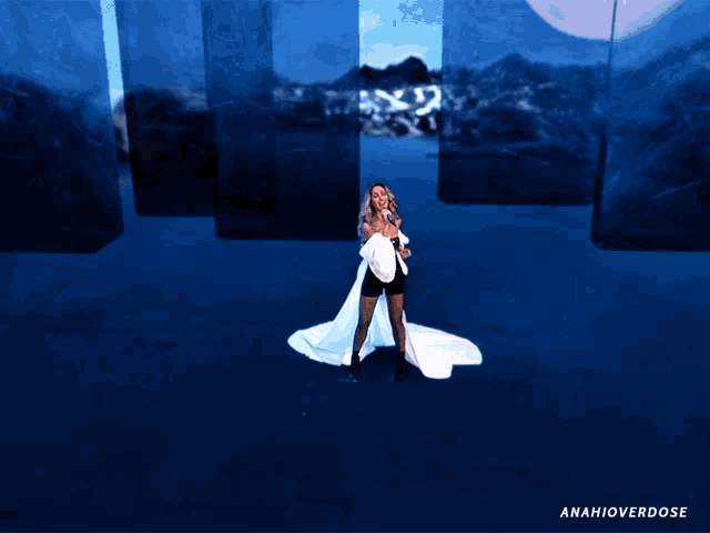 a woman in a white dress is singing in front of a blue background that says anahioverdose on it