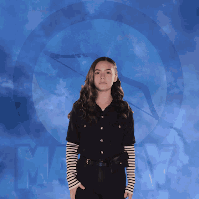 a woman flexes her muscles in front of a blue background with the word marvel