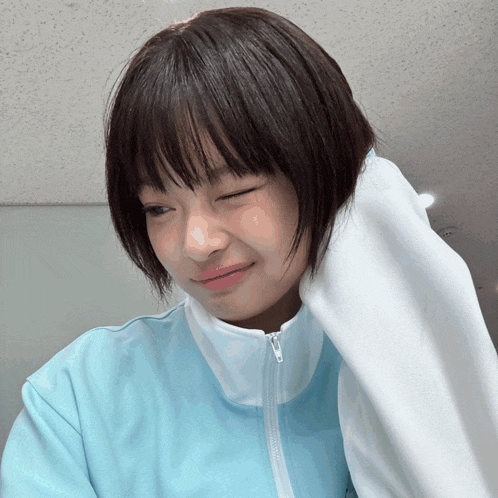 a girl with short hair is wearing a blue jacket