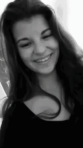 a black and white photo of a smiling woman with long hair
