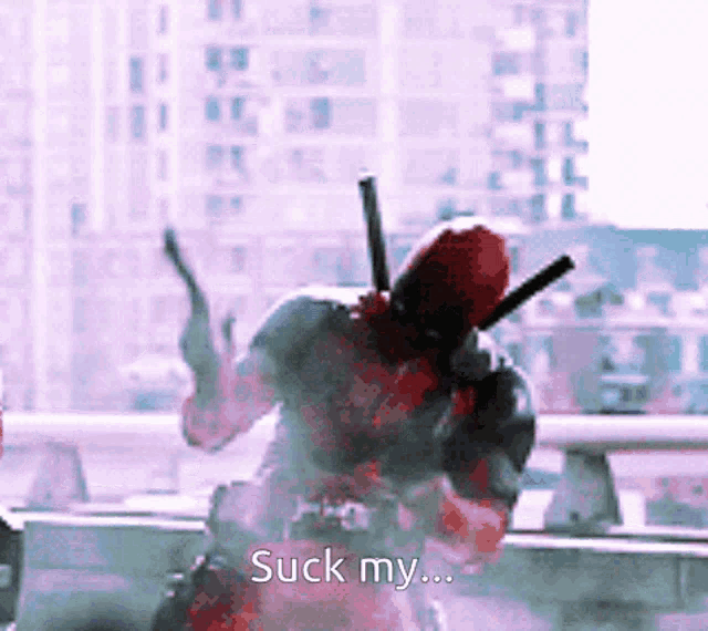 a man in a deadpool costume is holding two guns and says " suck my "