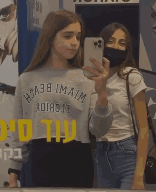 two girls are taking a selfie in front of a sign that says ' miami beach '