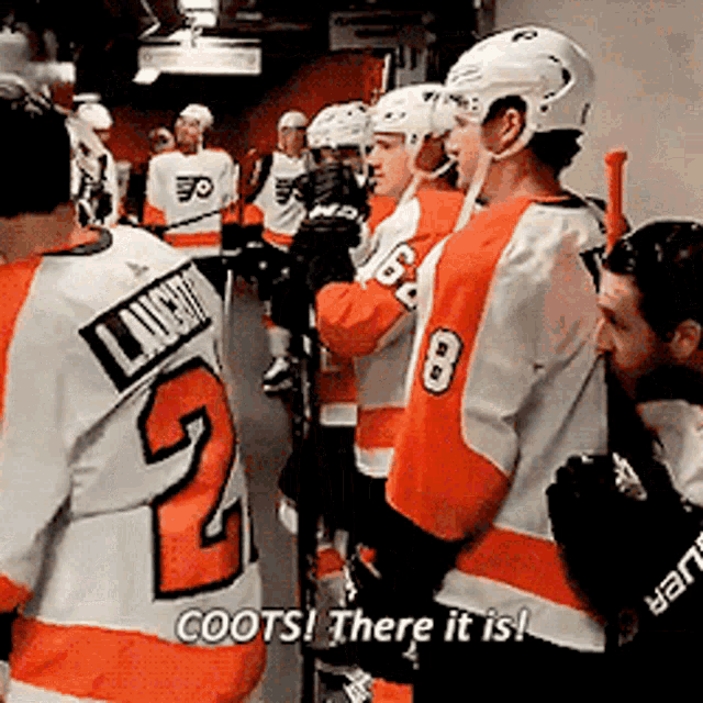 a group of hockey players are standing in a locker room and one of them is wearing a jersey with the number 2 on it