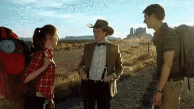 a man in a cowboy hat is talking to a woman in a plaid shirt .