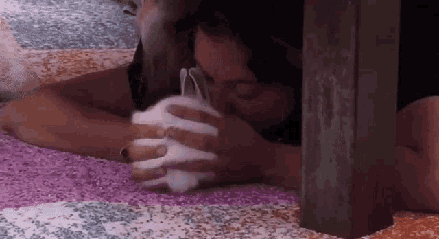 a woman is laying on a bed holding a white rabbit