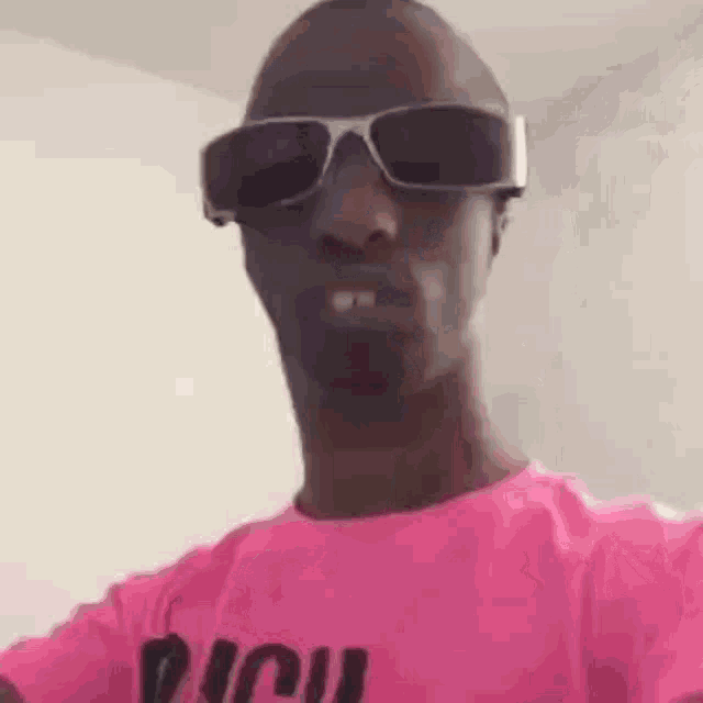 the man is wearing sunglasses and a pink shirt .