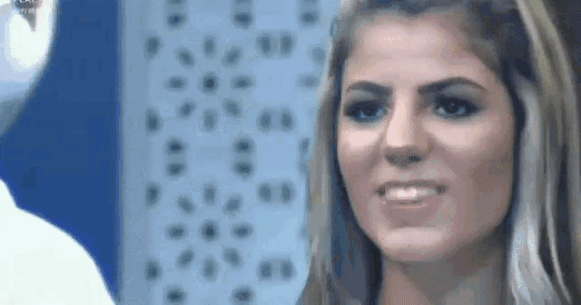 a woman is smiling and looking at the camera while standing in front of a wall .