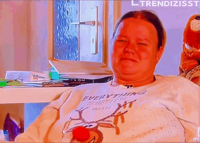 a woman wearing a sweater that says everything is better with a red nose .