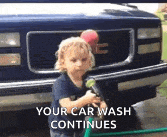 a little boy is washing a car with a hose and a ball .