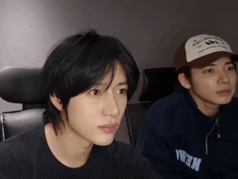 two young men are sitting next to each other and one of them is wearing a baseball cap that says ' new york '