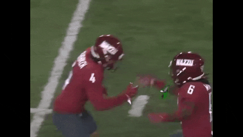 two football players are hugging each other on the field . one of the players is wearing a number 4 jersey .