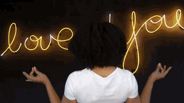 a woman is standing in front of a neon sign that says love you