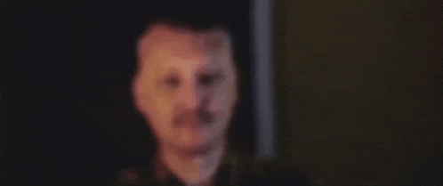 a close up of a man 's face with a mustache looking at the camera .