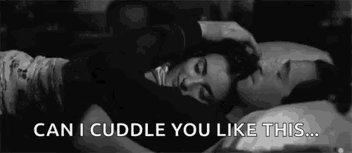 a man and a woman are laying in bed and the man is petting the woman 's hair .