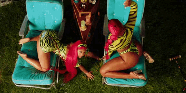 two women with pink hair are sitting on lawn chairs in the grass