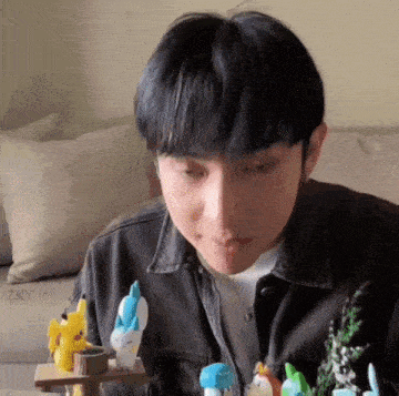 a young man is sitting on a couch eating a candy bar with toys in the background .