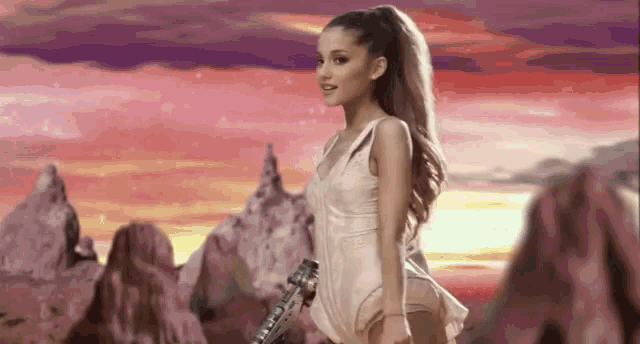 a woman in a white dress is holding a guitar in front of a mountain range