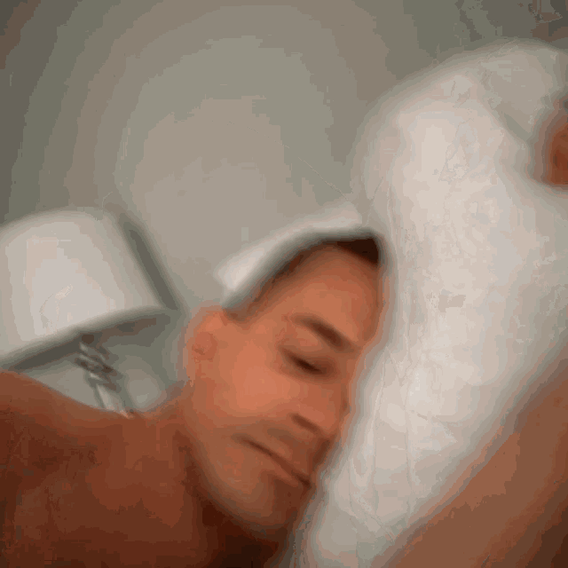 a man is laying in bed with a white pillow